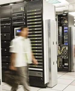 Three multi-ethnic technicians working in a large computer server room. Three multi-ethnic technicians working in a large computer server room.